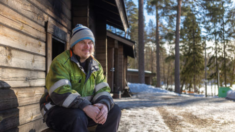 Kuusijärven savusaunoja lämmittävä Heikki Nieminen istuu savusaunan edessä.